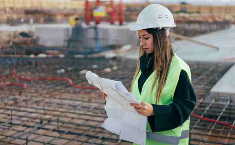 A women engineer reading blueprint at construction site