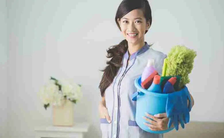 A professional house cleaner tidying up a living room