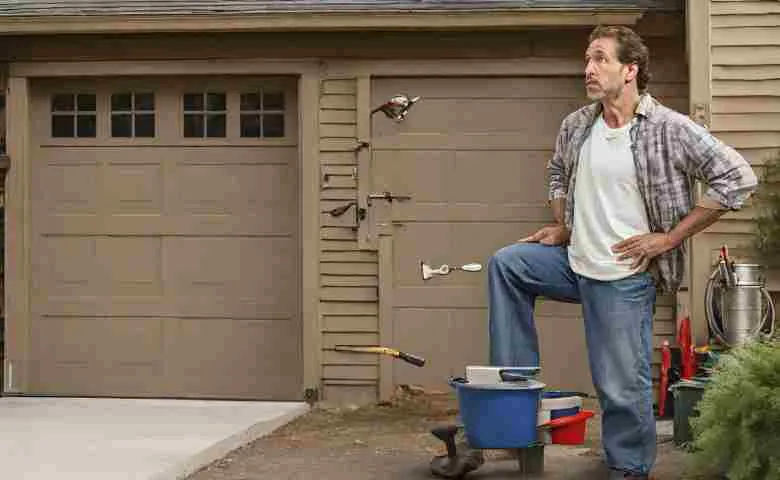 A homeowner inspecting a broken garage door