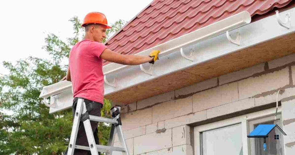 Professional contractors installing modern gutters on a suburban home